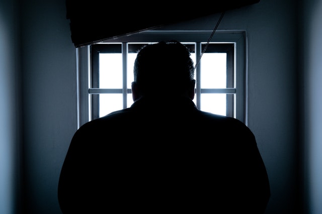Internationaal strafrecht: veroordeeld in het buitenland persoon zittend in donkere gevangenisruimte met een raam